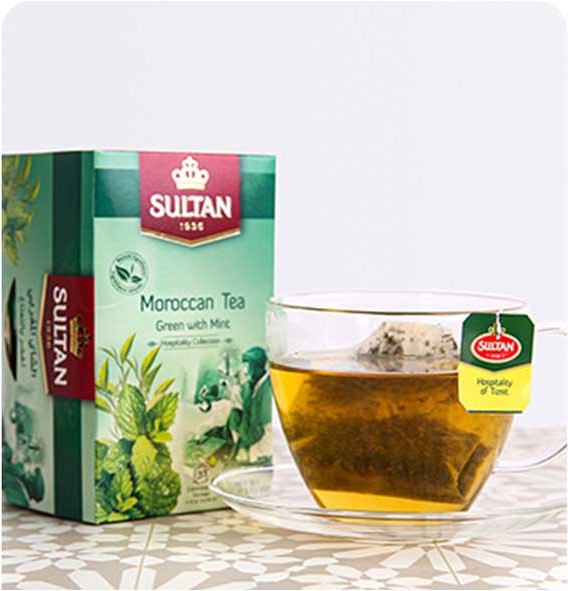 Sultan Moroccan Tea green box with a glass cup filled with tea on a patterned table